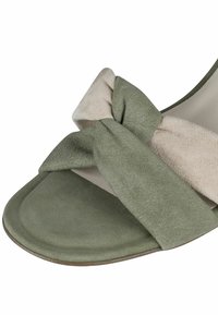 Suède sandalen met een platte zool in een lichtgroen en beige kleurenpalet. Opvallend strikdetail op de band voegt textuur en interessantheid toe.