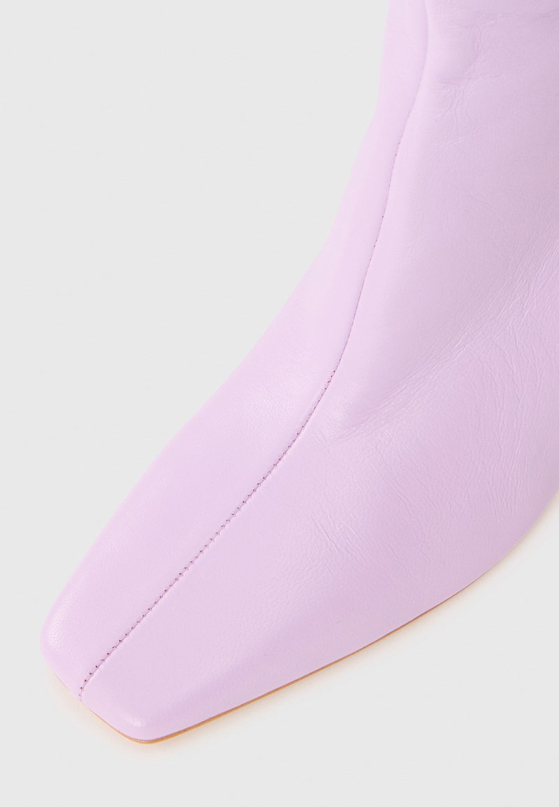 Liliowy skórzany botek za kostkę z ostrym noskiem i minimalnym przeszyciem. Gładka faktura z eleganckim, nowoczesnym designem.