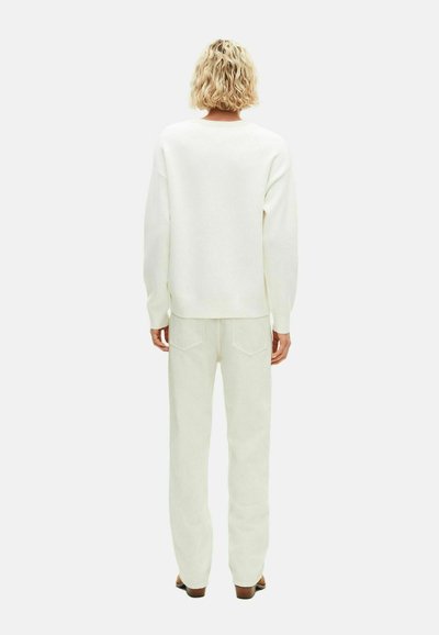 Hvid, oversized sweatshirt med lange ærmer, parret med lysecreme bukser med vide ben. Blødt stof, minimalistisk design, ingen synlige mønstre eller accenter.