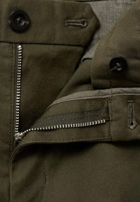 Green fabric with a smooth texture; features a metal zipper, black button, and side pocket detail for added functionality.