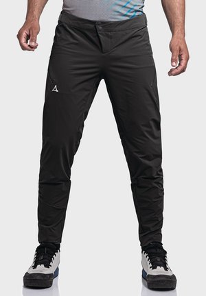 Black athletic pants with a slim fit, two side pockets, and a smooth texture. Features a white logo on the left thigh.