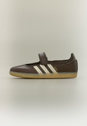 Chaussure Adidas Samba marron avec des bandes blanches, semelle en gomme et une seule bride Velcro sur le dessus, vue de profil.