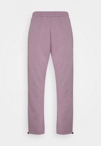 Lila Jogginghose mit Kordelzugbund, schmal zulaufenden Beinen, seitlichen Taschen und elastischen Bündchen. Weicher, strukturierter Stoff. Minimalistisches Design.