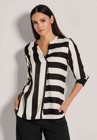 Zwart-witte gestreepte blouse met een V-hals, driekwart mouwen en een relaxte pasvorm. Zacht materiaal met een strakke afwerking.