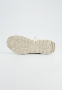 Schuhsohle in Off-White mit strukturiertem Zickzackmuster, ausgestattet mit erhabenen Griffen für Traktion und einem glatten, abgerundeten Zehenbereich.