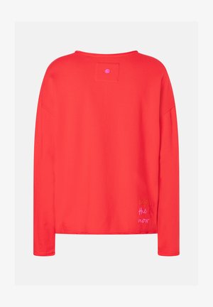 Helles rotes Langarmshirt mit einem kleinen Patch und einem Knopf in der Nähe des Kragens, und "genieße den Augenblick" in buntem Faden in der Nähe des Saums gestickt.