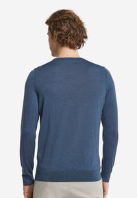 Mörkblå långärmad tröja med rund halsringning, texturerad finish, ribbade muddar och kant. Tyget verkar lätt och slätt.