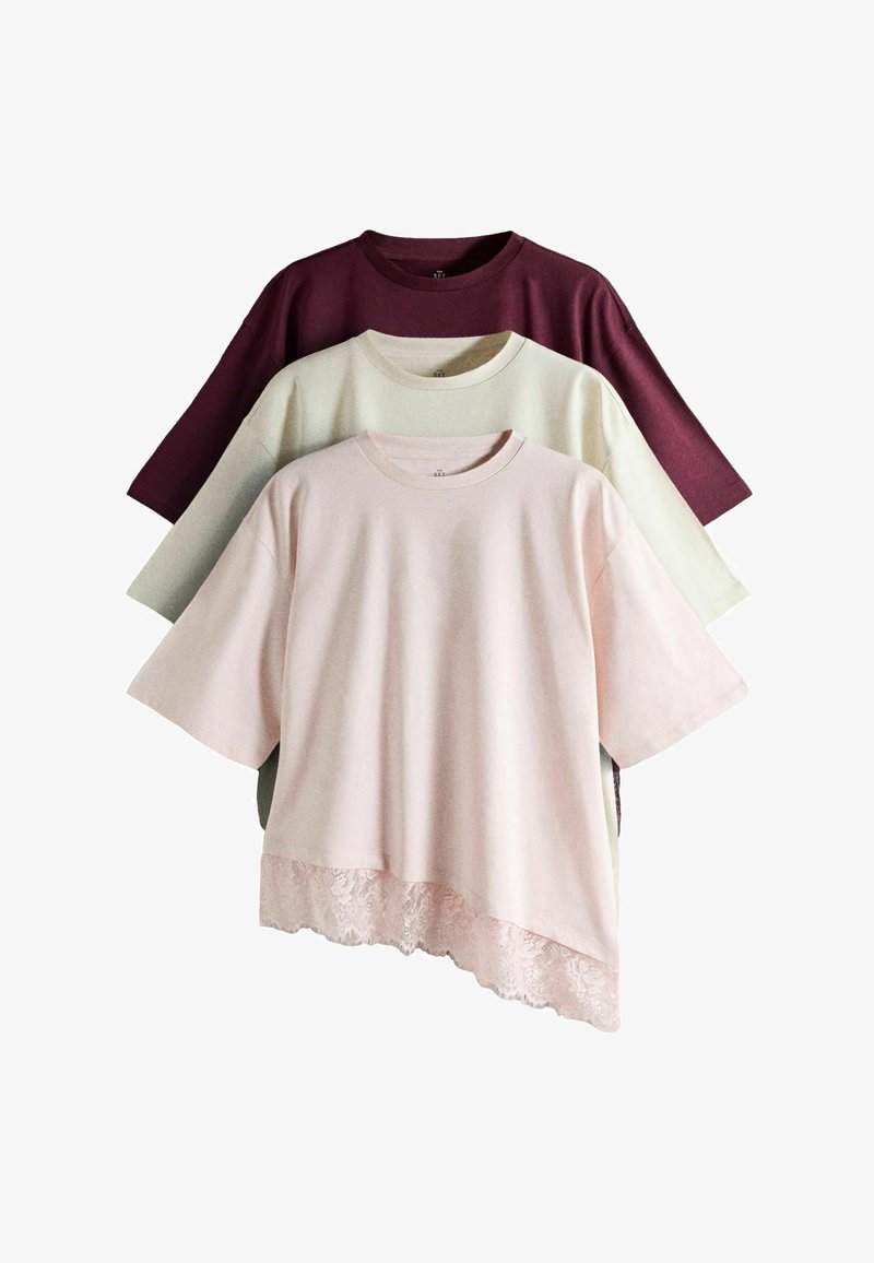 Three short-sleeve crew neck shirts in burgundy, cream, and light pink, with the pink shirt featuring an asymmetrical lace hem.