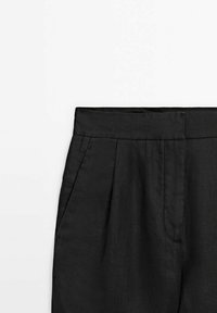Pantalon noir taille haute avec plis et poches latérales, présenté de la taille à mi-cuisse sur un fond blanc.