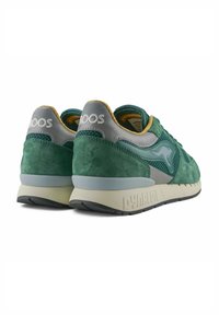 Sneaker verde in suede con accenti grigi, pannelli in rete e colli imbottiti. Presenta una suola testurizzata bianco sporco con il marchio "DYNACOIL".