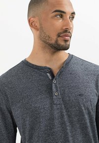 Mørkegrå henley skjorte lavet af tekstureret stof, med tre knapper og et diskret logo på brystet.