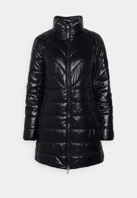Veste longue matelassée brillante noire avec col montant, fermeture éclair frontale, poches latérales et motif de couture en chevrons.