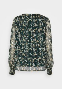Blouse transparente à manches longues avec un motif floral abstrait en vert foncé, beige et blanc, dotée de poignets froncés et d'une coupe ample.