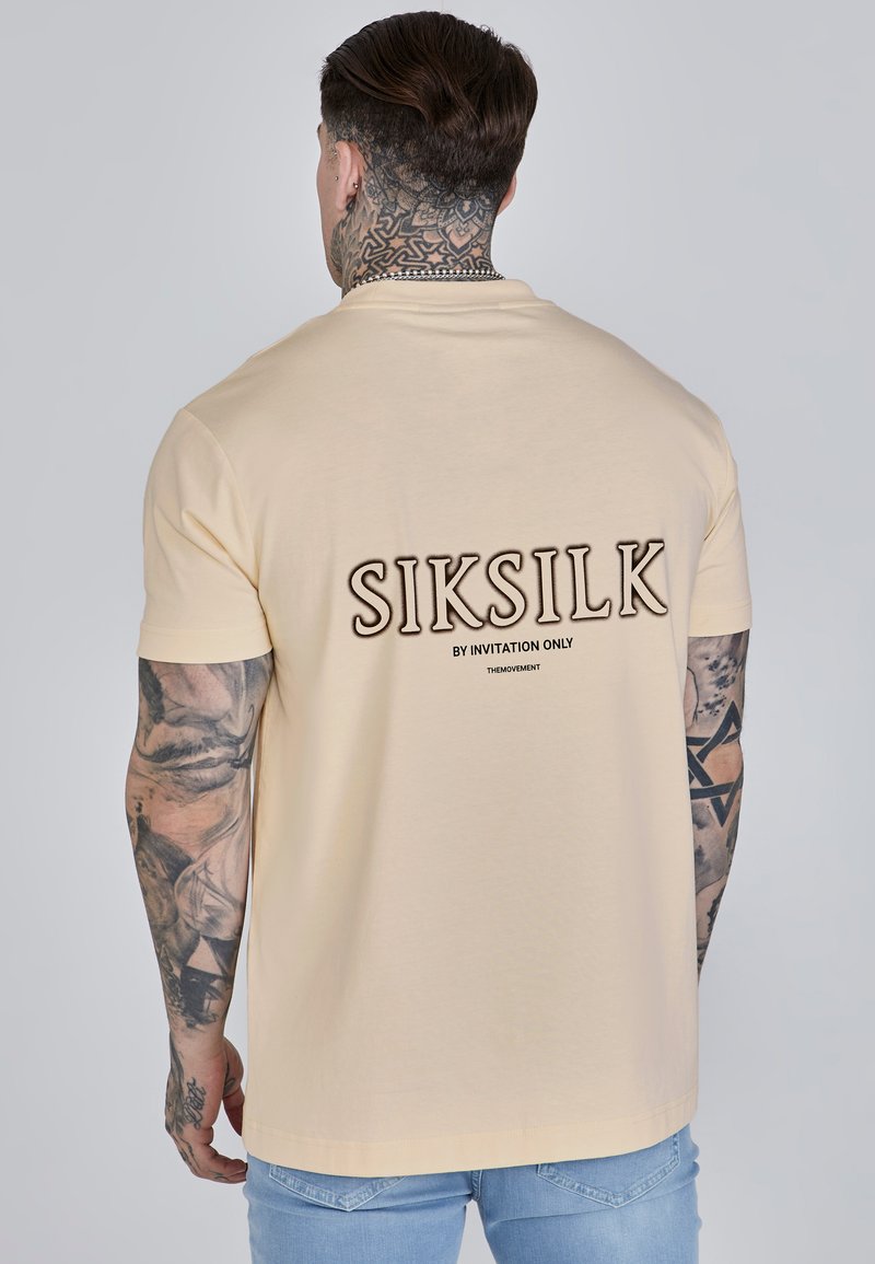 Beige, rövidujjú póló, kerek nyakkivágással, a hátsó részén "SIKSILK BY INVITATION ONLY" felirattal, vastag betűkkel. Puha pamut anyag.