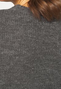 Tessuto di maglione grigio lavorato a maglia con una texture a coste, che mostra fibre morbide. Il colletto superiore è arrotondato e aderente al collo.