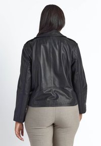 Sort læderjakke med en struktureret krave, tætsiddende design og glat tekstur. Har synlige syninger og en beskåret bagkant.