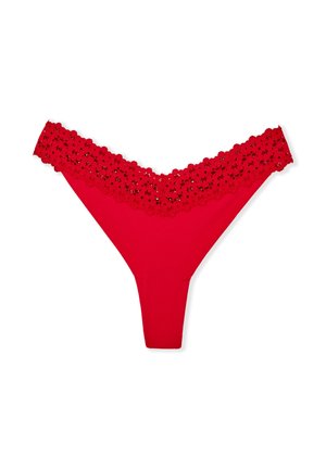 String rouge avec une ceinture en dentelle florale à bords festonnés, corps en tissu doux et conception à couverture minimale.