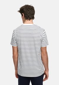 Hvit t-skjorte med marineblå horisontale striper, korte ermer, rund halslinning og avslappet passform, vist fra baksiden.