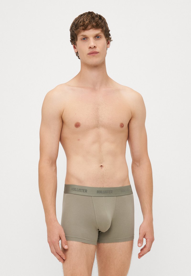 Olive green bokserki z miękkiej tkaniny, z elastycznym paskiem z logo i ciasnym krojem, zaprezentowane na modelu.