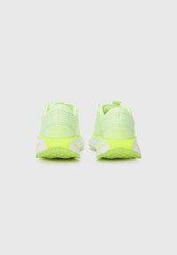 Chaussures de sport Nike en jaune néon éclatant avec une tige en maillage texturé, des accents blancs et verts, et une languette au talon.