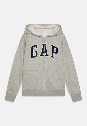 Felpa grigia con zip e interno morbido, caratterizzata da un grande logo navy "GAP" sulla parte anteriore e tasche frontali. Maniche e fondo a costine.