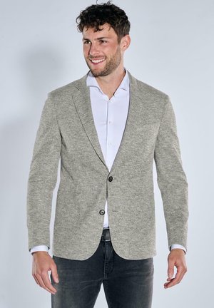 Light grey textured blazer with a two-button closure, notched lapels, and a slim fit, worn over a white shirt and dark jeans.