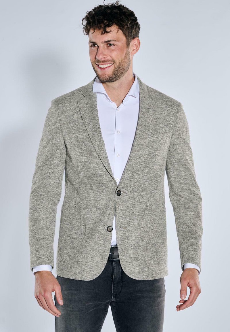 Light grey textured blazer with a two-button closure, notched lapels, and a slim fit, worn over a white shirt and dark jeans.