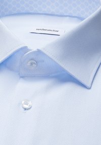 Chemise habillée bleu clair texturée avec col pointu et boutons blancs, présentant une étiquette de marque "seidensticker" à l'intérieur du col.