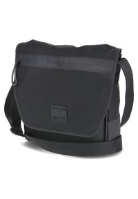 Black messenger bag made of fabric with a smooth texture. Features a top flap, zip closure, adjustable strap, and logo patch on the front.