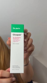 Mano che tiene una confezione per la cura della pelle Dr. Jart+ Cicapair Soothing Treatment con packaging verde e bianco e testo in inglese e francese.