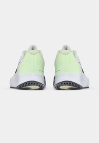 Ζευγάρι άσπρων και ανοιχτόχρωμων πράσινων αθλητικών παπουτσιών που φαίνονται από το πίσω μέρος, με υφασμάτινες μαύρες και μπεζ σόλες σε λευκό φόντο.