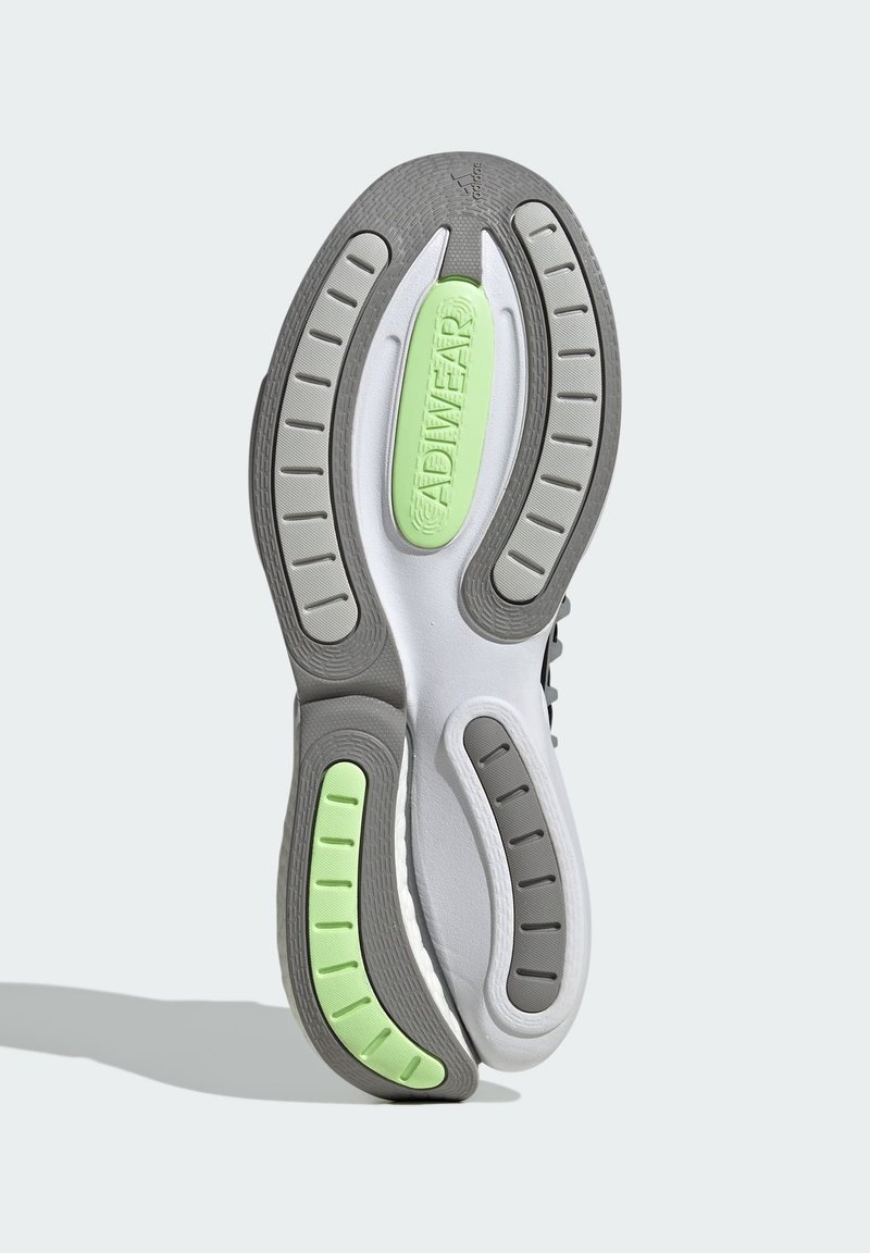 Semelle de sneaker grise et blanche avec caoutchouc texturé, présentant un accent vert, des rainures pour l'adhérence et une section centrale lisse.