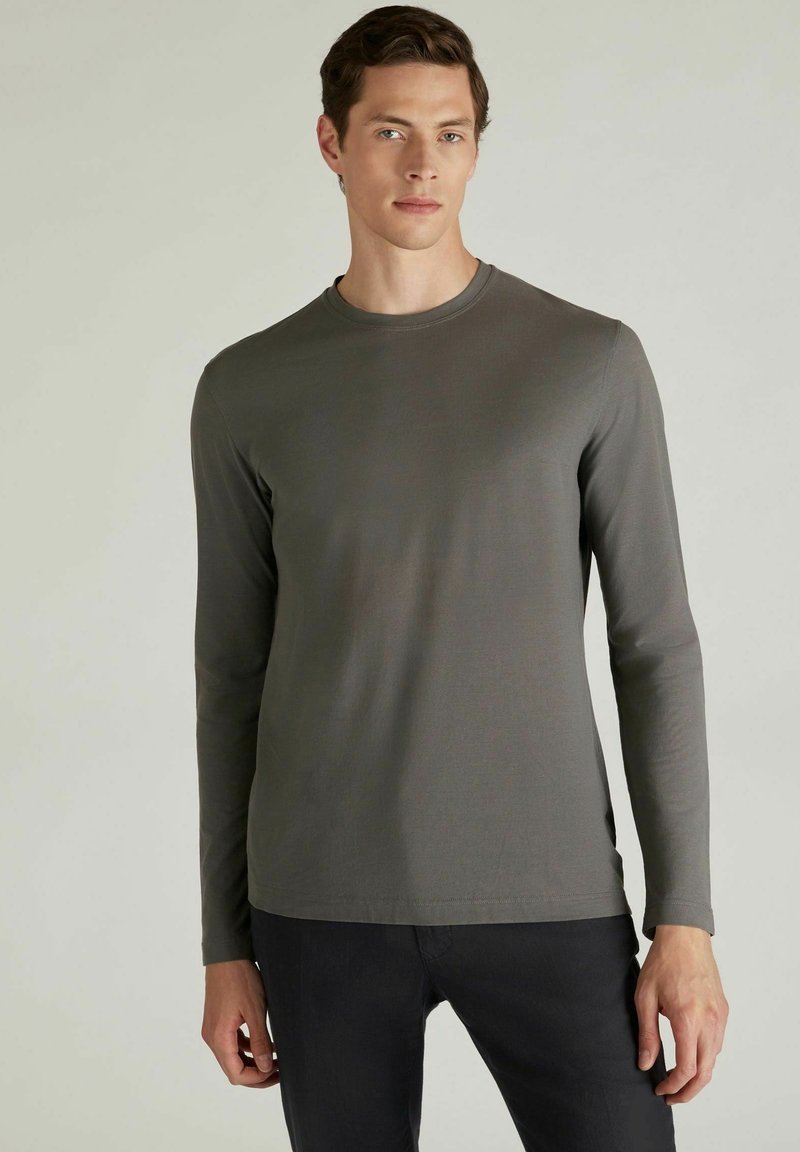 T-shirt grigio a maniche lunghe realizzato in tessuto morbido, con scollatura rotonda e vestibilità regolare, abbinato a pantaloni neri.