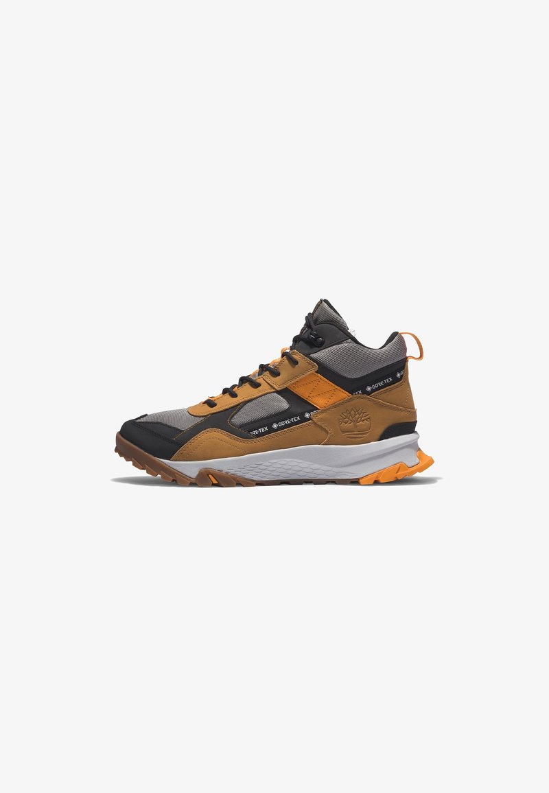 Baskets de randonnée montantes marron, noir et gris avec panneaux Gore-Tex, une semelle intermédiaire blanche et des accents orange, affichant le logo Timberland sur le côté.