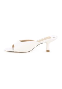 Mules de tacón abierto en blanco con un acabado suave, diseño superior curvado y un tacón de bloque de 5 cm. Costuras visibles a lo largo de los bordes.