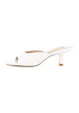 Mules de tacón abierto en blanco con un acabado suave, diseño superior curvado y un tacón de bloque de 5 cm. Costuras visibles a lo largo de los bordes.