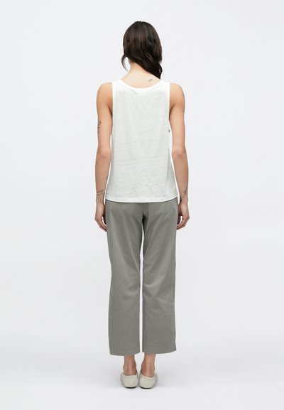 Αμάνικη μπλούζα ανοιχτού γκρι χρώματος με άνετη γραμμή, συνδυασμένη με παντελόνι ανοιχτού γκρι χρώματος, ψηλόμεσο, με φαρδιές παντελόνες, και μπεζ παπούτσια τύπου slip-on.