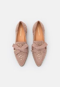 Baleríny s špičatou špičkou v světle růžové velurové kůži, zdobené zlatými hroty a velkou textilní mašlí na přední straně. Hladký vnitřek s viditelným názvem značky.