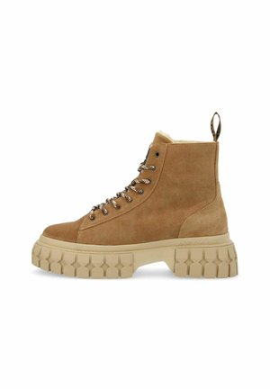 Stivaletti alla caviglia in suede marrone con una robusta suola in gomma beige, design con lacci e un passante sul retro. Presentano una texture con battistrada a forma di stella.