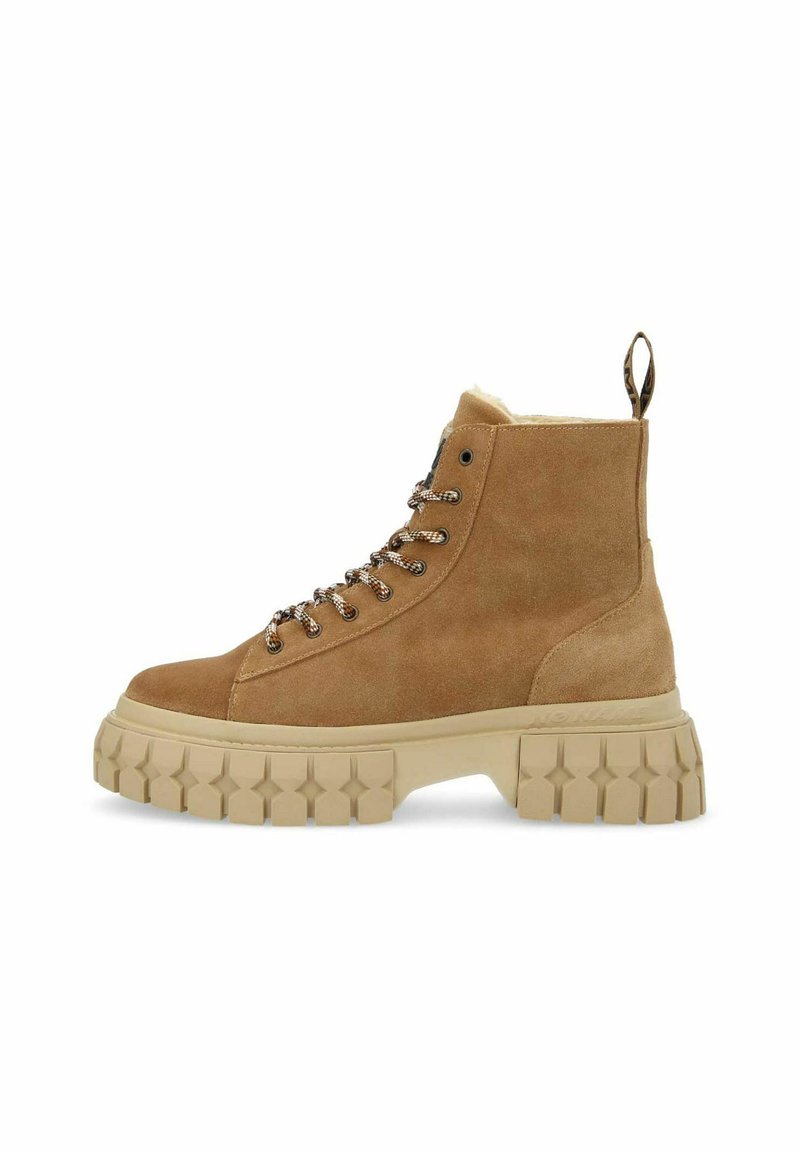 Stivaletti alla caviglia in suede marrone con una robusta suola in gomma beige, design con lacci e un passante sul retro. Presentano una texture con battistrada a forma di stella.