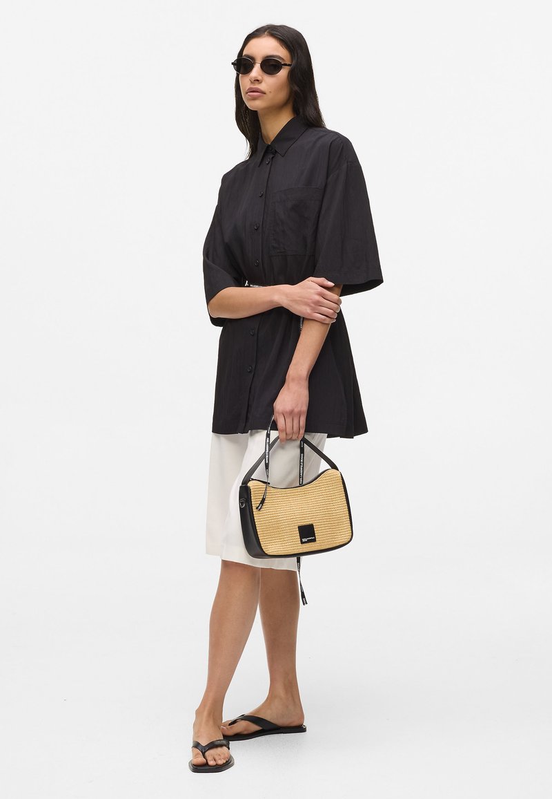 Schwarzes kurzärmeliges Hemd zum Knöpfen, cremefarbener Rock, schwarze Zehentrenner und eine zweifarbige Handtasche mit gewebter Textur und Logodetail.