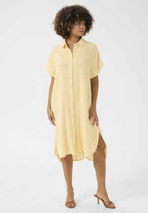Korte gele shirtdress met een kraag, knopen aan de voorkant en korte mouwen. Heeft zijsplitten en een gestructureerde, lichtgewicht stof.