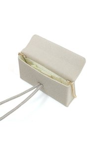 Beige stoffen handtas met een gestructureerd oppervlak, ritssluiting en interne compartimenten, voorzien van een dunne schouderriem en gouden hardware accenten.