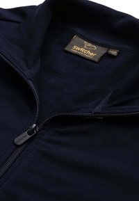 Maglione zip-up blu navy con colletto a coste, caratterizzato da una zip in metallo e un'etichetta con la scritta "Switcher" in giallo. Tessuto morbido.