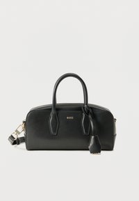 Μαύρο δερμάτινο τσάντα χειρός με δύο λαβές, αποσπώμενο ιμάντα ώμου και μικρή ετικέτα που κρέμεται από τη μία λαβή, πάνω σε απλό λευκό φόντο.