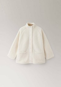 Veste polaire blanc cassé avec col montant, boutons pression à l'avant, manches longues et deux poches avant sur un fond neutre.