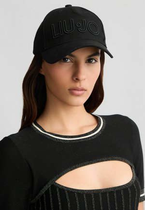 Cappello nero con visiera curva e logo "LIU·JO" in rilievo. Realizzato in tessuto testurizzato, presenta un design aderente. Indossato con un top nero con dettagli.