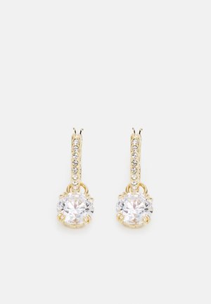 Paire de boucles d'oreilles pendantes dorées avec des rangées verticales de petits cristaux et de grands pendentifs ronds en pierres précieuses claires.