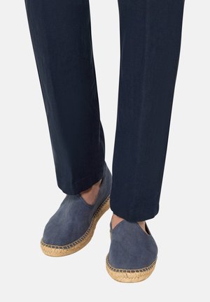 Pantalon bleu marine associé à des espadrilles en daim bleu avec semelles en corde de jute naturelle.