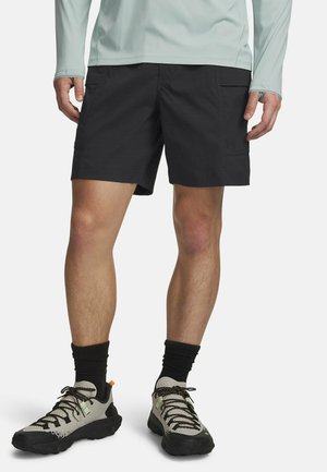 Black cargo shorts with side pockets, made from lightweight material, paired with grey and black athletic shoes featuring textured soles and patterned laces.